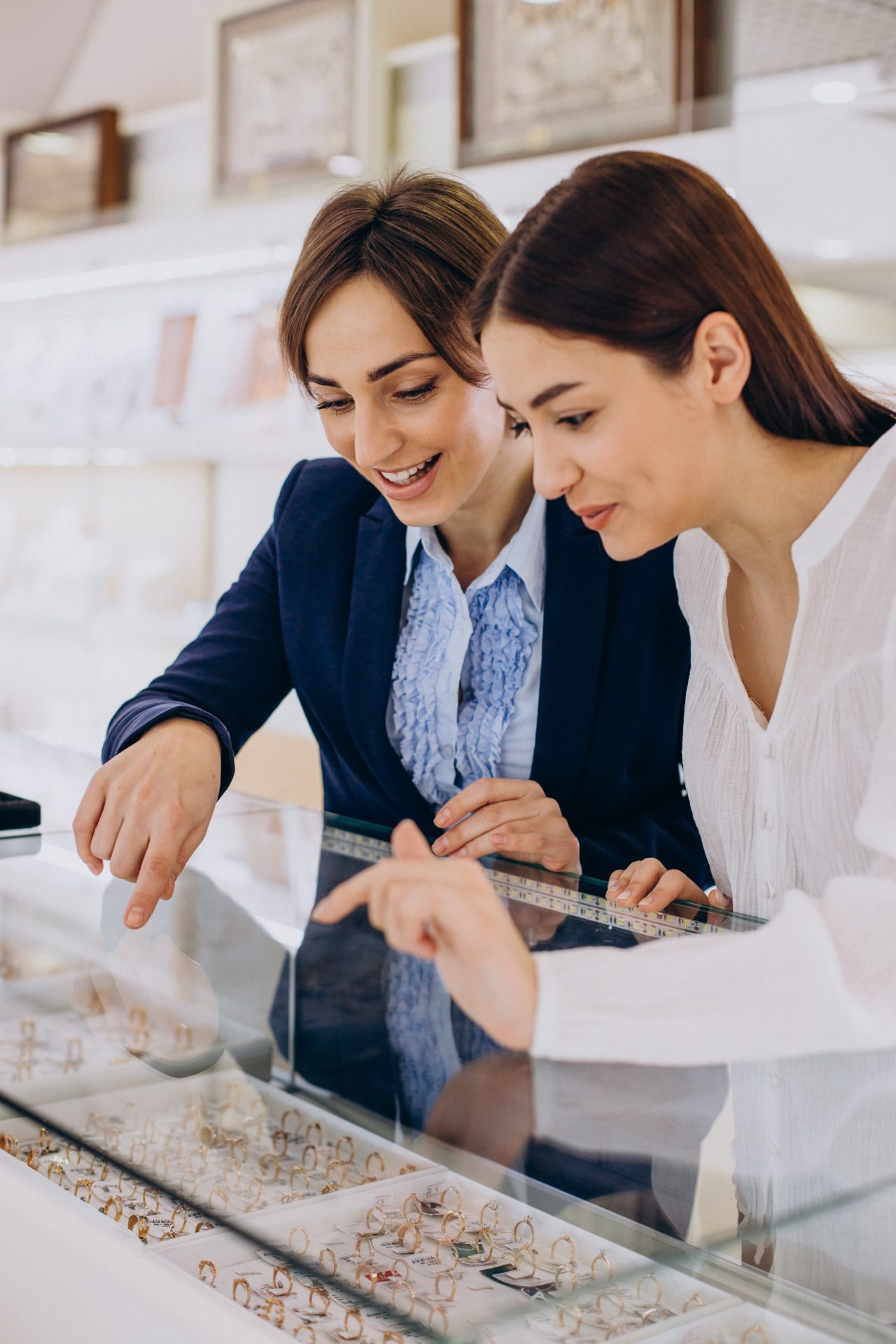 a jewelry saleswoman helping a customer, pointing out a specific item